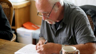 Elderly man writing in his journal with a pen