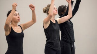Students wearing all black with their hands raised