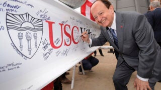 USC President C. L. Max Nikias signs a beam during the spire-raising ceremony marking the halfway point of USC Village construction