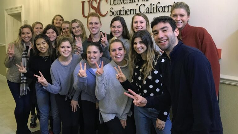 USC Annenberg students posing doing the fight on sign at USC's London office