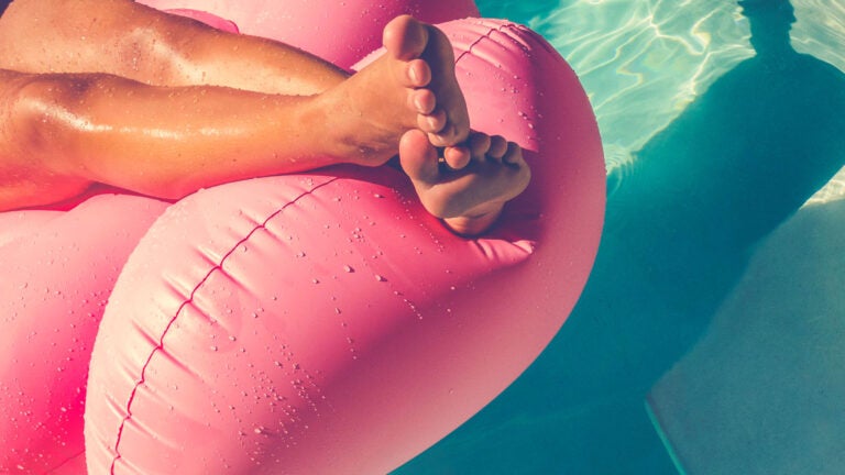 woman floating on a pink inflatable in swimming pool