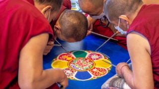 Monks from the Drepung Gomang Monastery in Tibet work on the sand mandala at the USC Pacific Asia Museum.