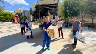 USC doctor Kenji Inaba, right, and other health care workers unpack protective medical supplies donated from the set of ABC’s Grey’s Anatomy.