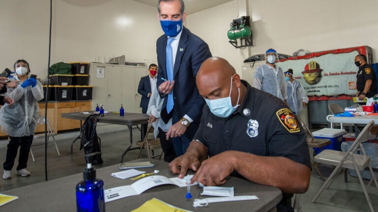 Los Angeles City Fire Captain Leon Dunn takes a rapid antigen test as Mayor Eric Garcetti observes. (USC Photo/Gus Ruelas)