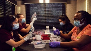 USC pharmacy professionals Allison Chacon, Kimberly Moore, Anna Sarkissian, and Kari Trotter, from left, prepare COVID-19 vaccine doses at Dodger Stadium. (