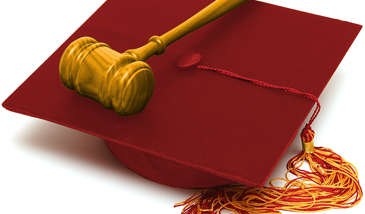 A wooden gavel sitting on top of a cardinal graduation cap