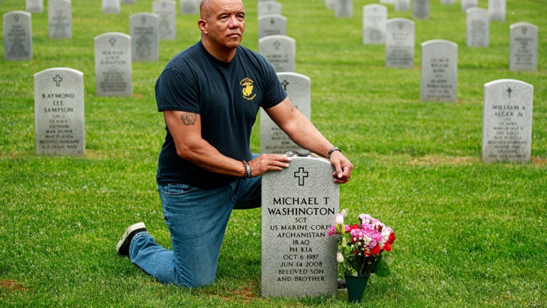 Mike Washington kneeling next to his son's gravestone