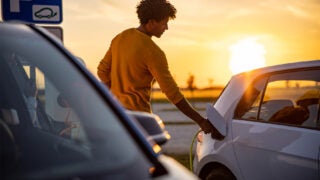 individual inserting plug into electric vehicle