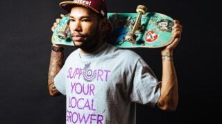 Miles Jackson holding a skateboard behind his head