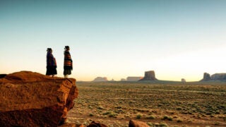 Two people in front of a desert background