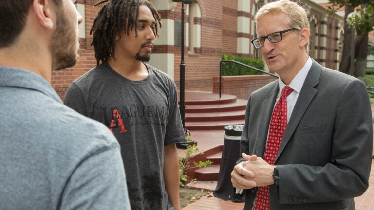 Andrew T. Guzman speaking with two students