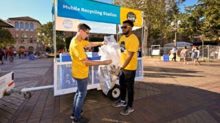 two students holding recycling bags filled with cans