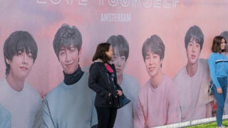 Young women in front of BTS billboard