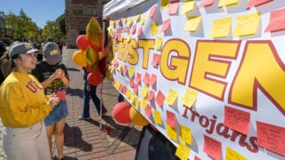 Students writing on post-it notes in front of a banner entitled