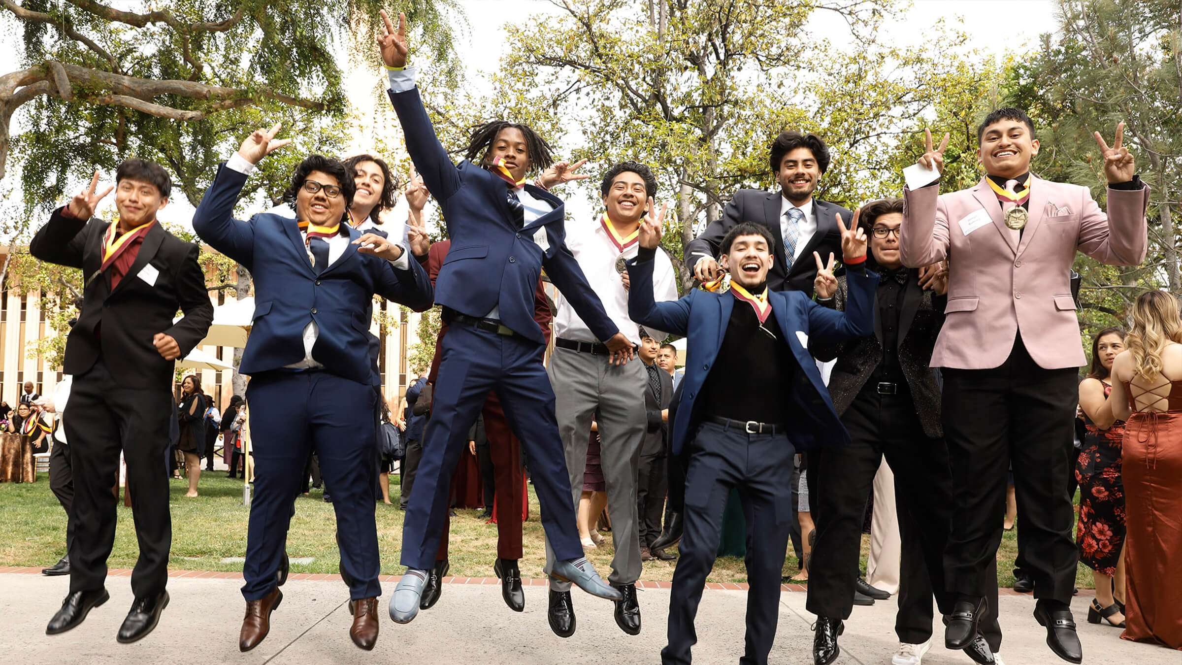 A group of graduates at the NAI Gala jumping in the air throwing the Fight On symbol.