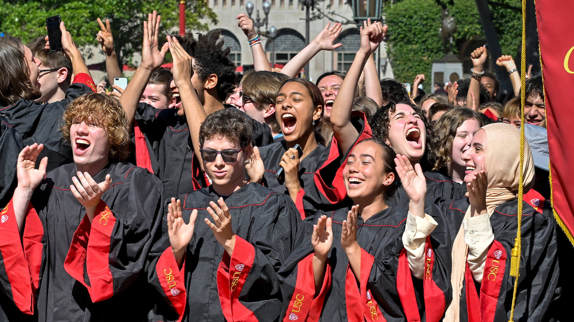 Incoming Trojans in graduation gowns clap and cheer as their school is introduced during USC’s new student convocation.