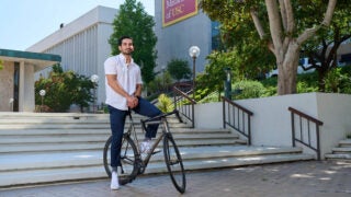 Sebouh J. Bazikian on a bike in front of a Keck School of Medicine USC building.