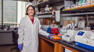 Marlena Fejzo, smiling in a lab with scientific equipment.