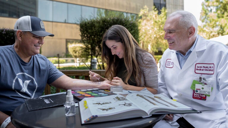 A female artist body painting a patient.