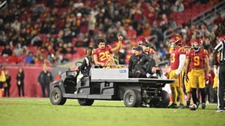 Travis Dye being removed from the field from an injury on top of a small vehicle