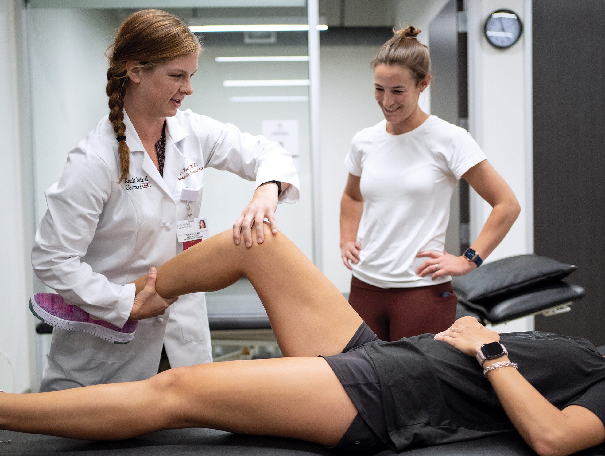 Dr. Cara Hall holding and putting pressure on the knee of an athlete