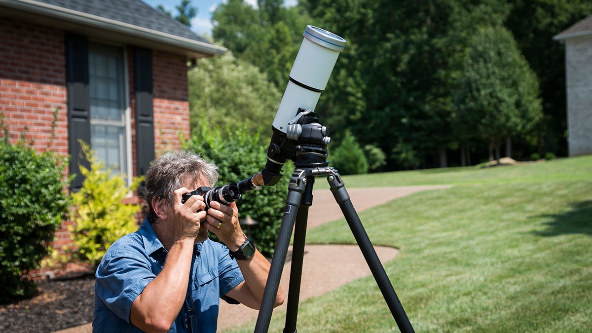 Adult male in 50's uses a solar telescope to observe the sun during a solar eclipse 