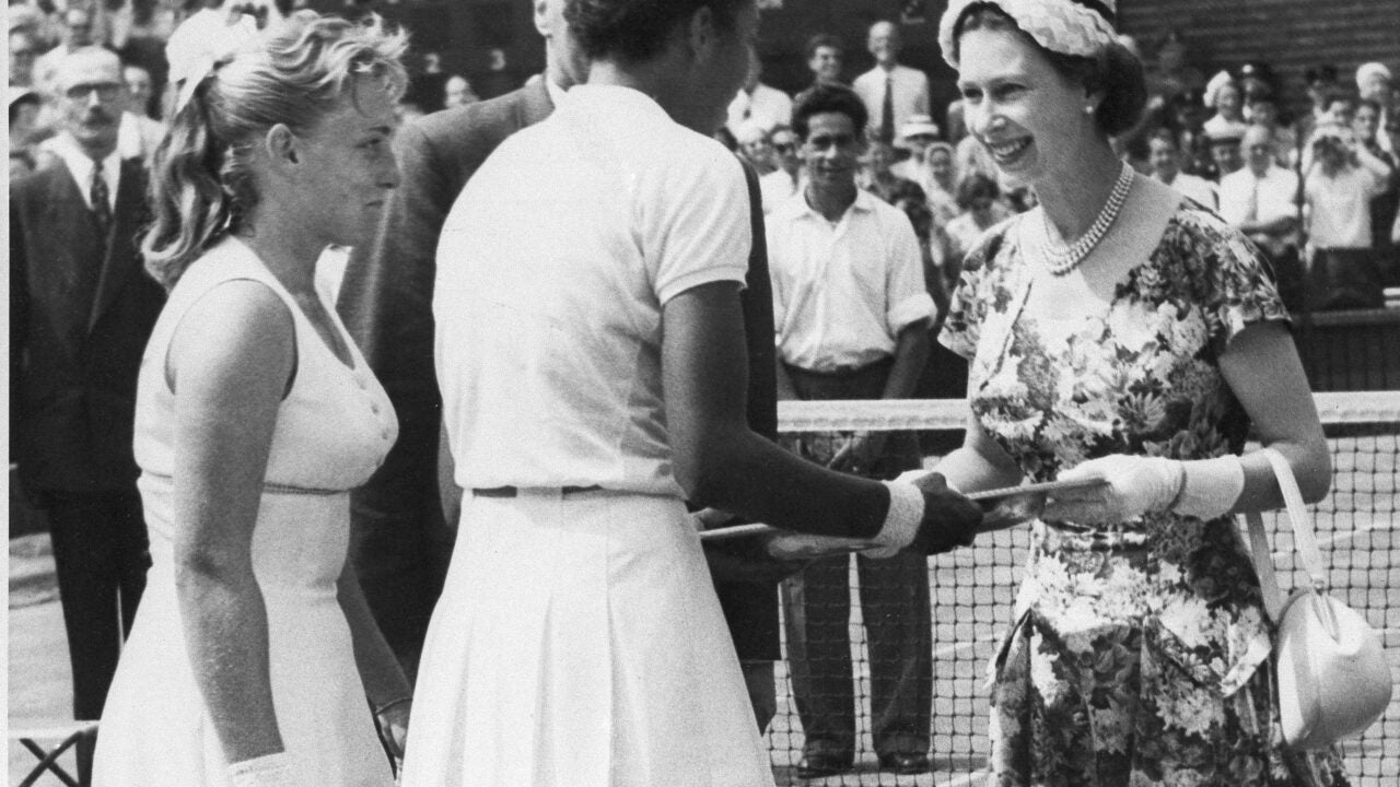 Queen Elizabeth II, right, presents the winners trophy to Althea Gibson (right) and Darlene Hard (left), who won the women's title in the All England Lawn Tennis Championship at Wimbledon in 1957. (Photo/AP)