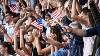 USA colored flags waving above large crowd on a stadium.