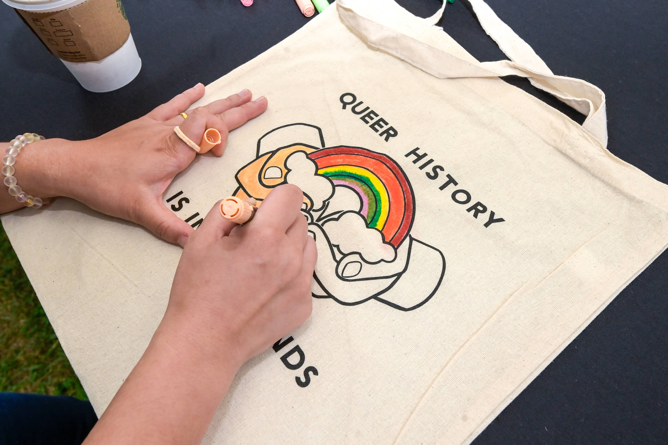 Student coloring 'Queer History' tote bag