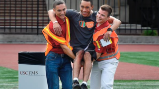 Two safety workers carrying a third person by the arms.