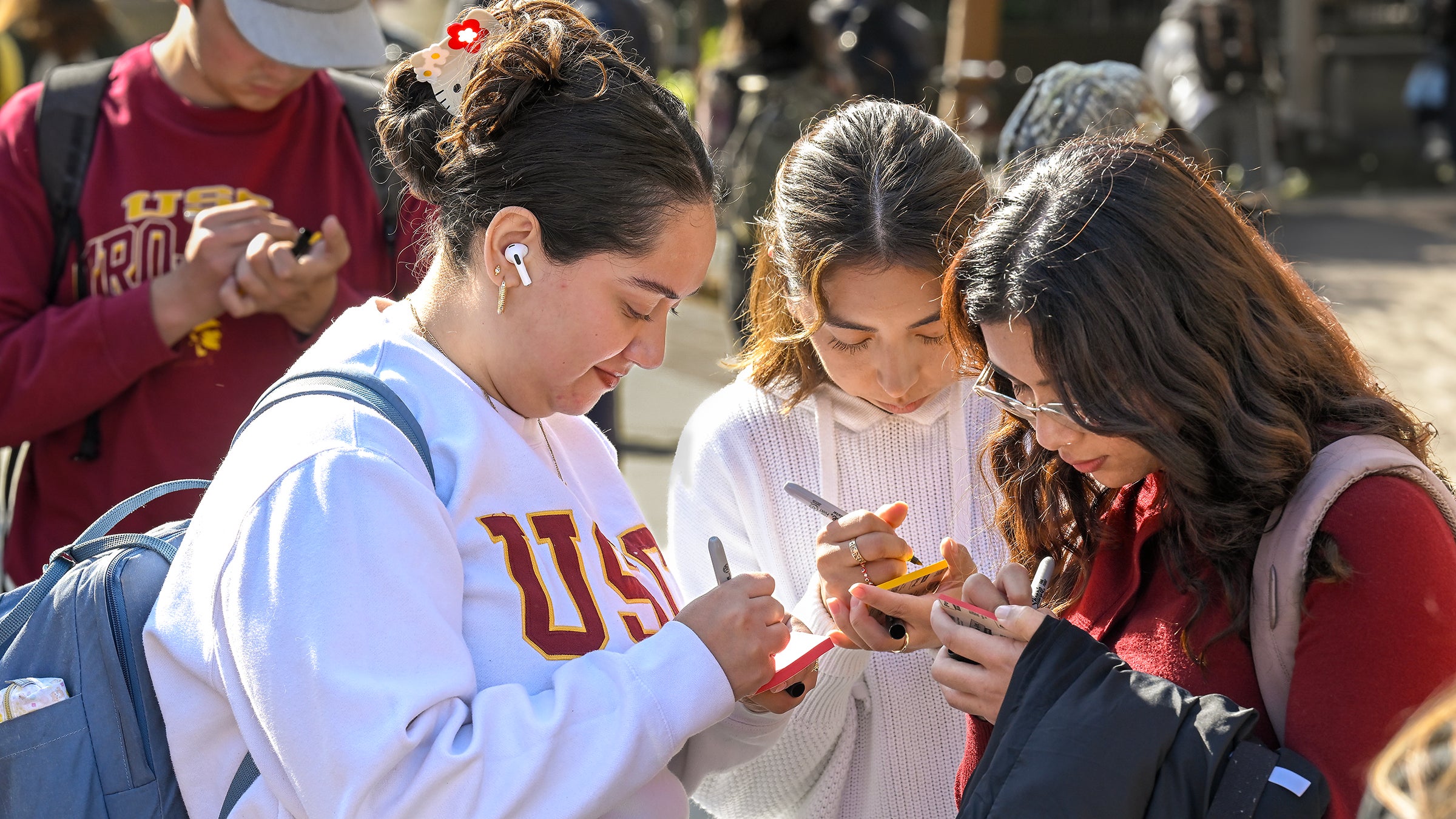 USC first-generation students: Halexandra Alvarenga, Michelle Esteban and Natalia Carrillo write messages for the board