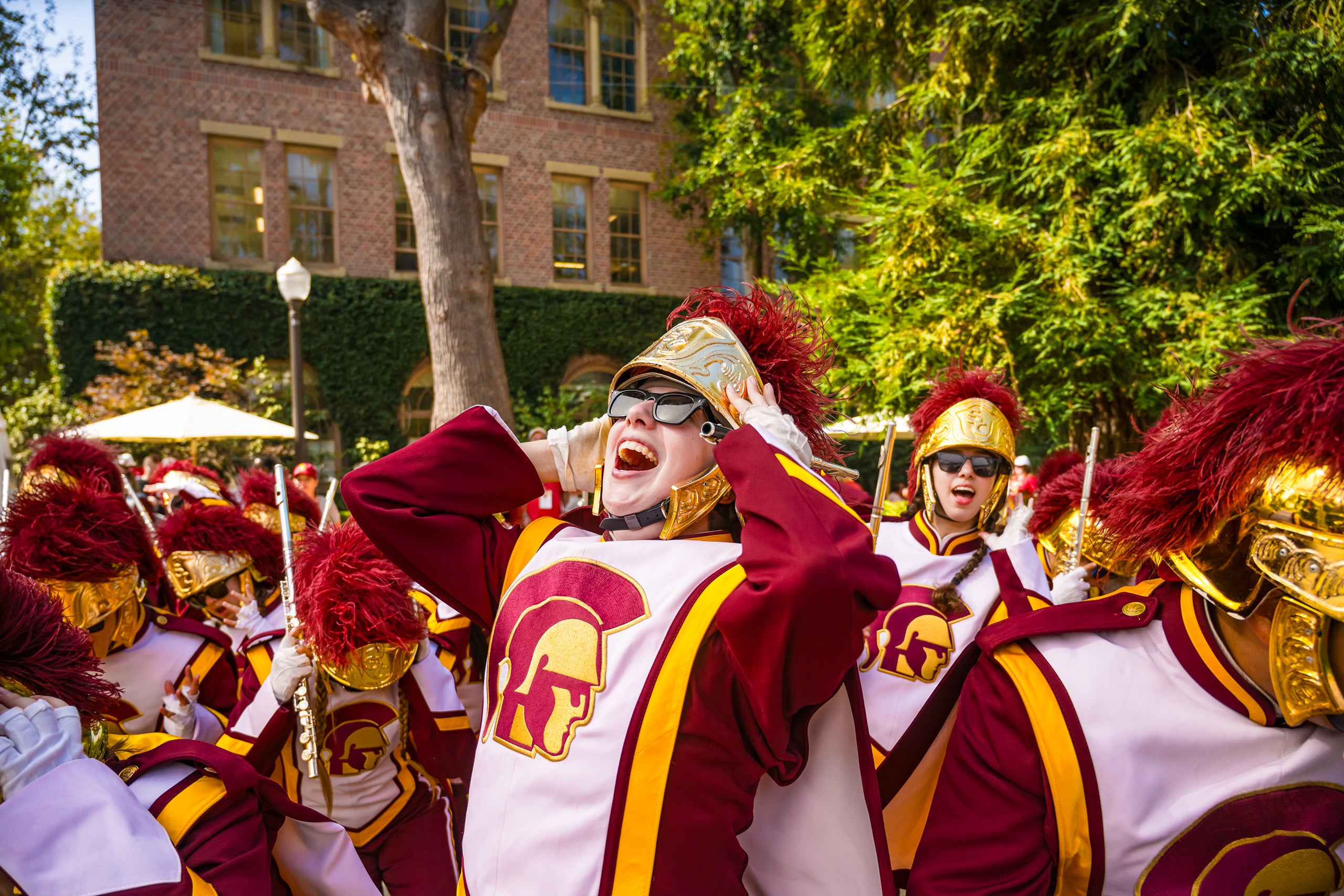 A diverse group of students in the USC marching band walking through the USC campus.