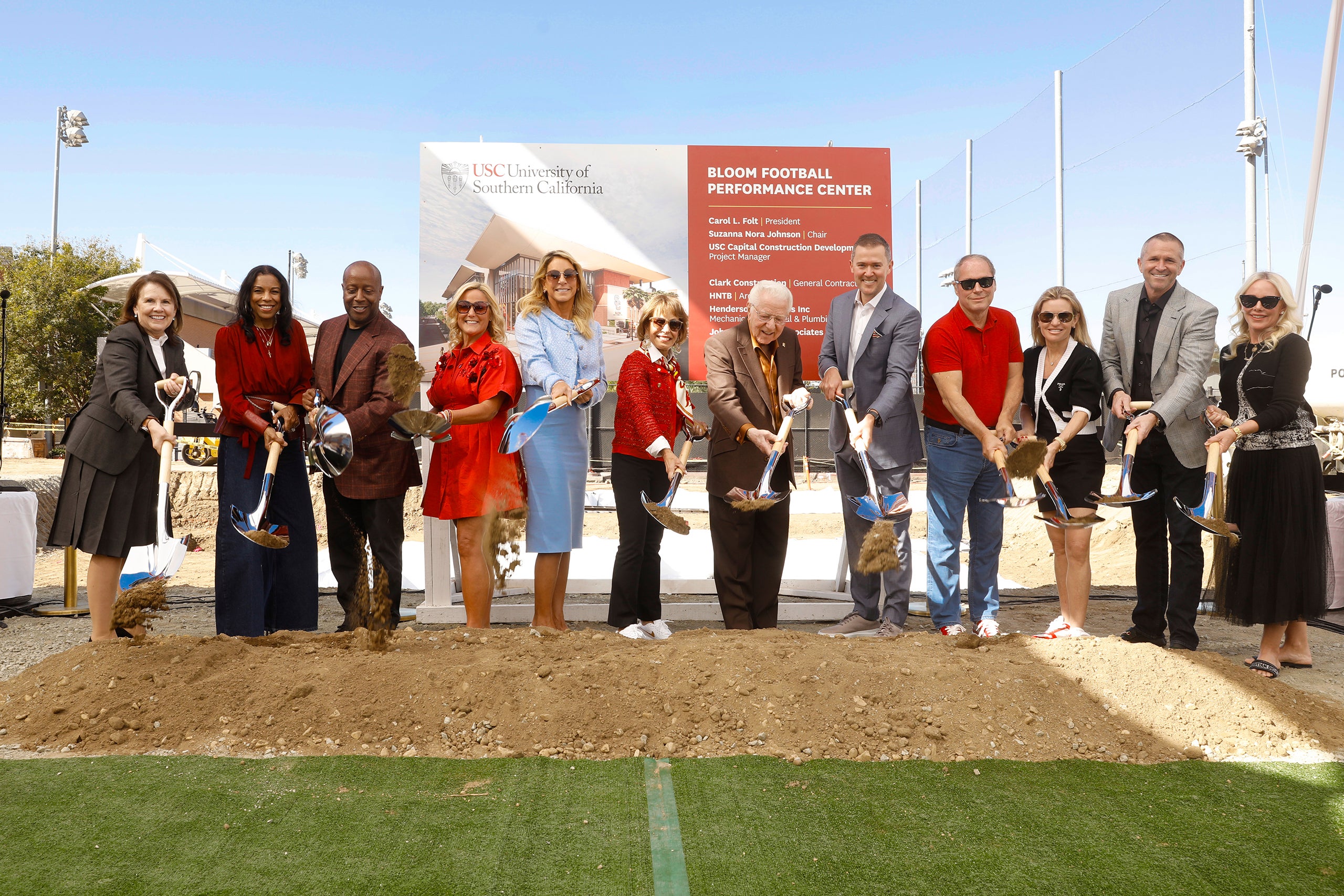 Group at USC groundbreaking with shovels, clear skies, stadium lights.