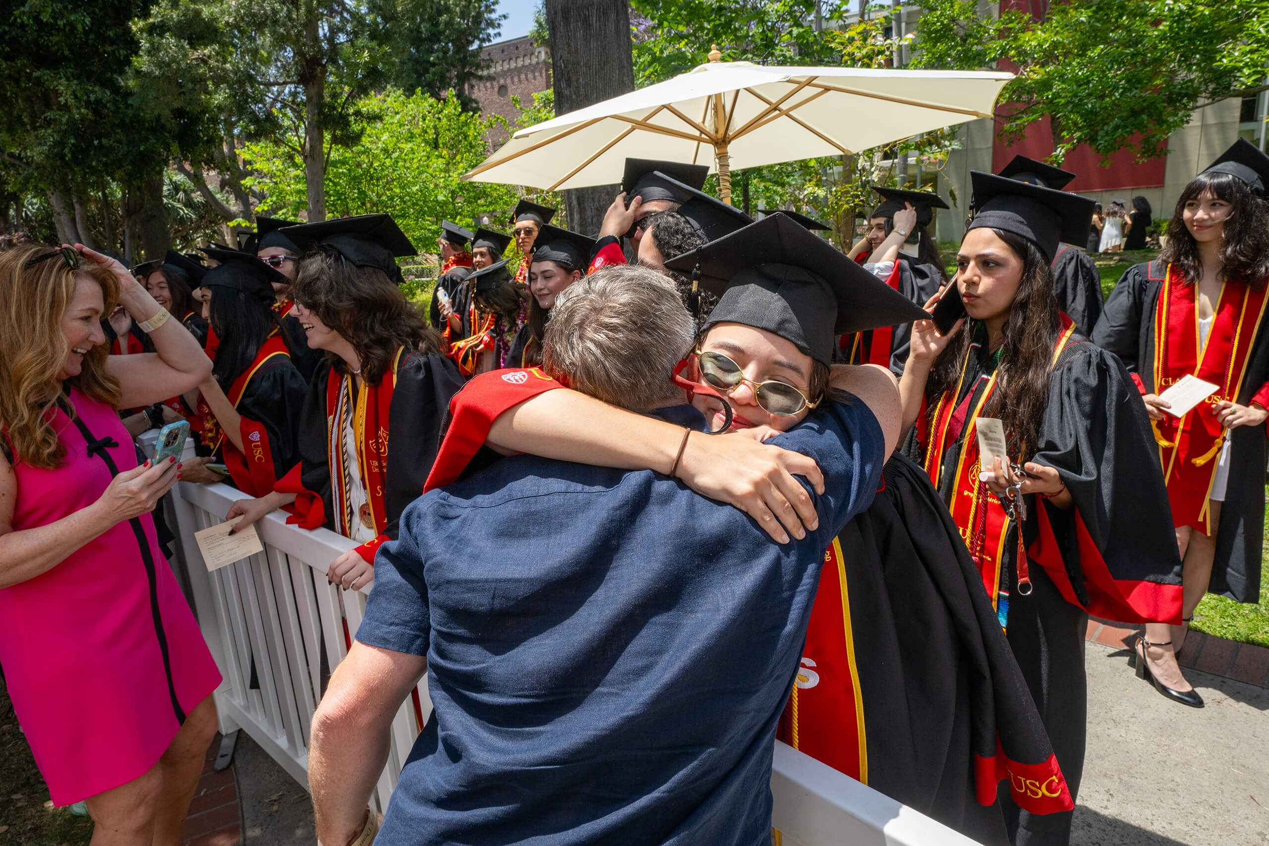 A proud parent hugs a USC graduate in red and gold regalia during the 2025 commencement celebration on campus.