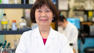 Jean Chen Shih in a lab and lab coat smiling