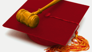 A brown wooden gavel sitting on top of a cardinal graduation cap
