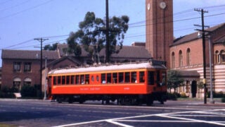 Orange and white Pacific Electric Santa Monica Airline street car passing by USC campus on Exposition Boulevard
