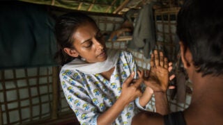 Physician Parveen Parmar, wearing a white shirt and checking out a person's hand