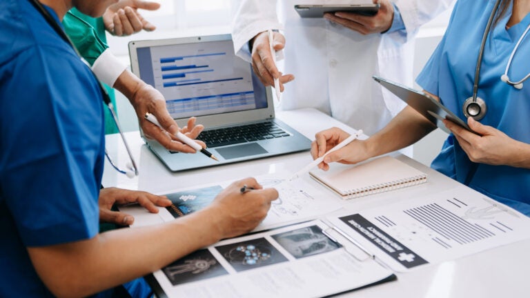 Doctors around a table with files and a computer