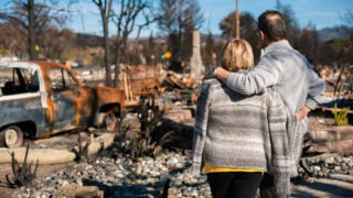 Couple looks over ruins of burned home