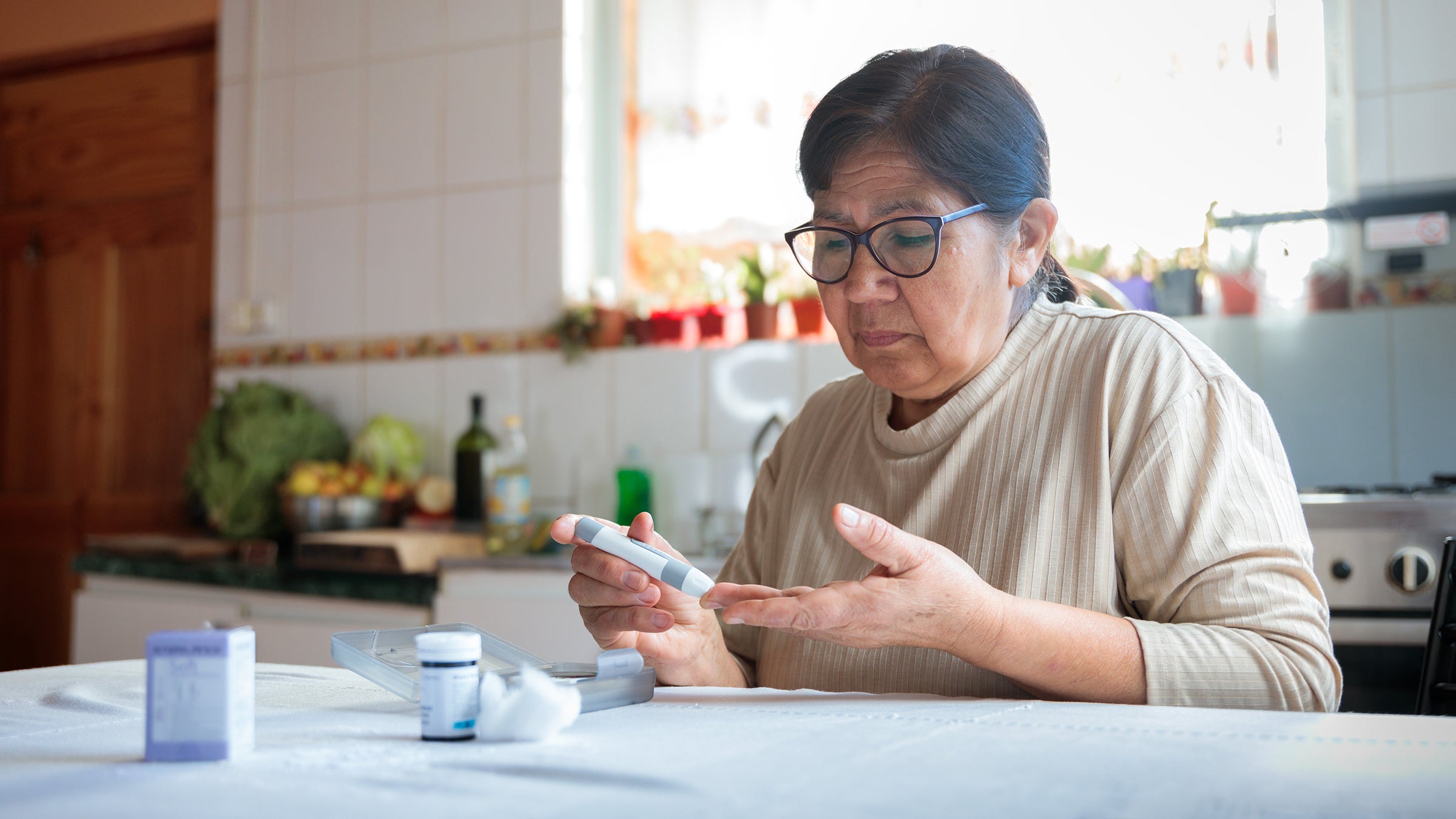 Elderly woman checking blood sugar level at home